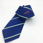 Hand-crafted silk ties with crest custom woven in blue with green and white lines